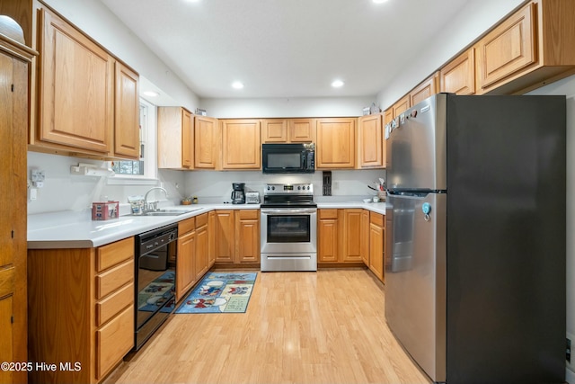 kitchen featuring sink, black appliances, and light hardwood / wood-style floors