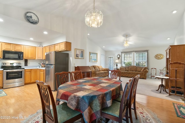 dining space with lofted ceiling, ceiling fan with notable chandelier, and light wood-type flooring