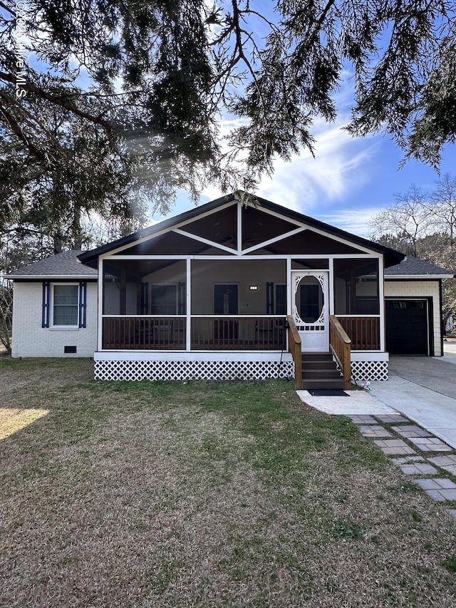 view of front of house with a garage, a sunroom, and a front lawn