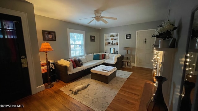 living room featuring ceiling fan, hardwood / wood-style floors, and built in features