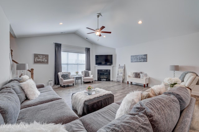 living room with ceiling fan, lofted ceiling, and light wood-type flooring