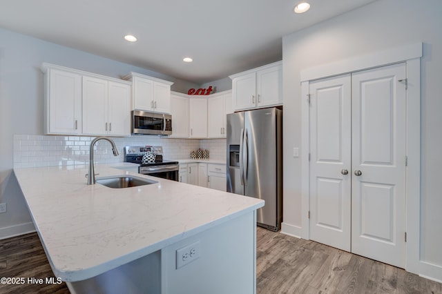 332 Grandview Dr, Hampstead, NC 28443 - kitchen featuring a peninsula, light stone countertops, appliances with stainless steel finishes, a sink, and light wood-style floors