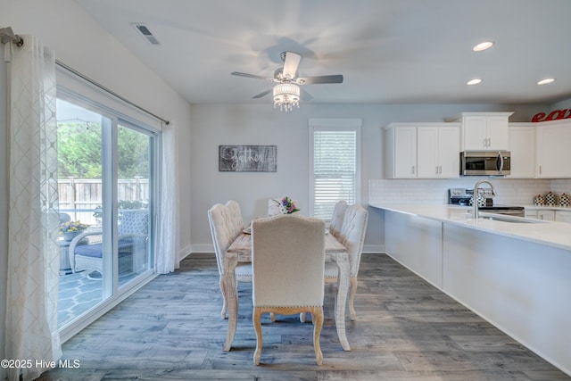 dining area featuring wood-type flooring, sink, and ceiling fan