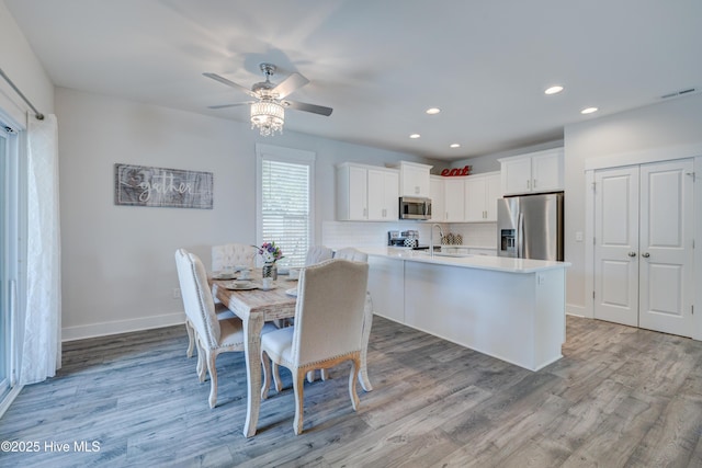 dining area featuring ceiling fan, sink, and light wood-type flooring