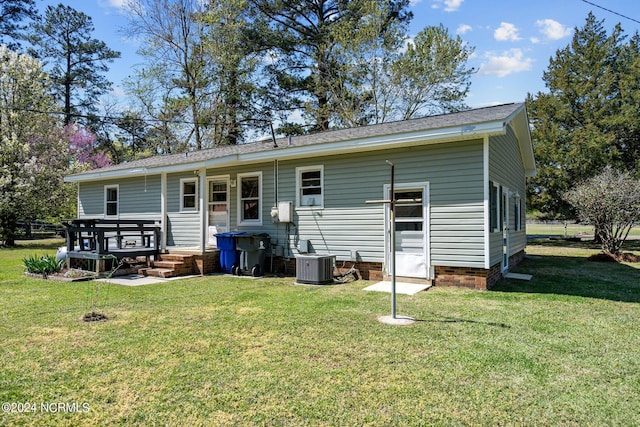 rear view of house featuring central air condition unit and a lawn