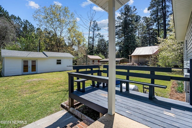 wooden deck with an outdoor structure, a yard, and french doors