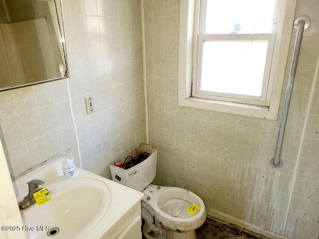 bathroom with toilet, vanity, and tile walls