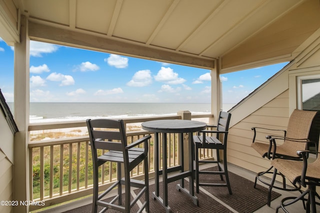 balcony with a water view and a view of the beach