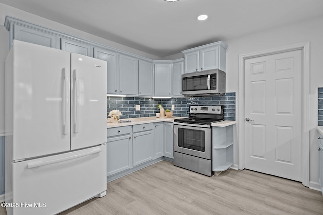 kitchen featuring white cabinetry, decorative backsplash, light hardwood / wood-style flooring, and stainless steel appliances