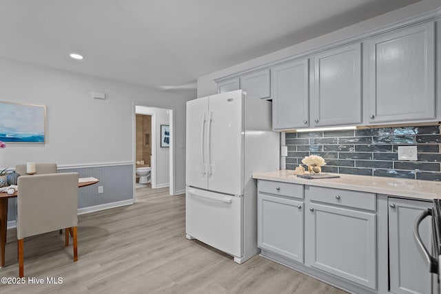 kitchen featuring gray cabinetry, tasteful backsplash, white fridge, and light hardwood / wood-style flooring