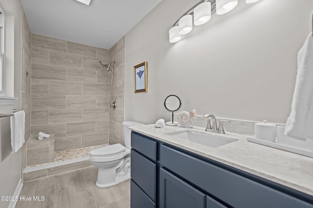 bathroom featuring vanity, hardwood / wood-style floors, toilet, and tiled shower