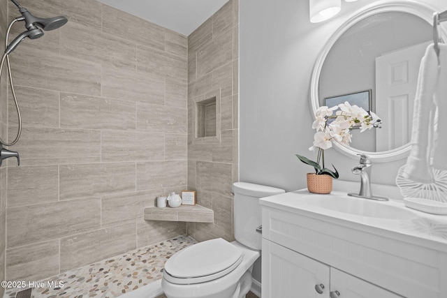 bathroom featuring vanity, tiled shower, and toilet