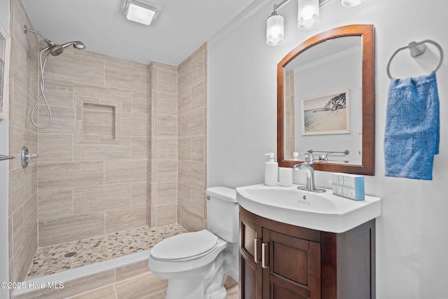 bathroom with vanity, tiled shower, and toilet