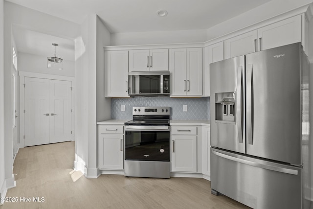 kitchen with tasteful backsplash, stainless steel appliances, light wood-type flooring, and white cabinets