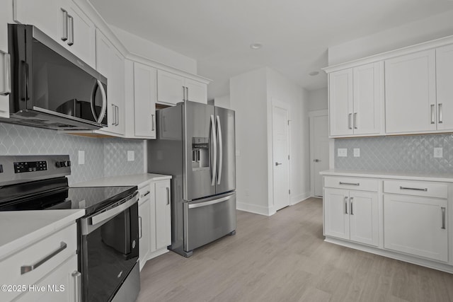 kitchen featuring stainless steel appliances, light wood-type flooring, decorative backsplash, and white cabinets