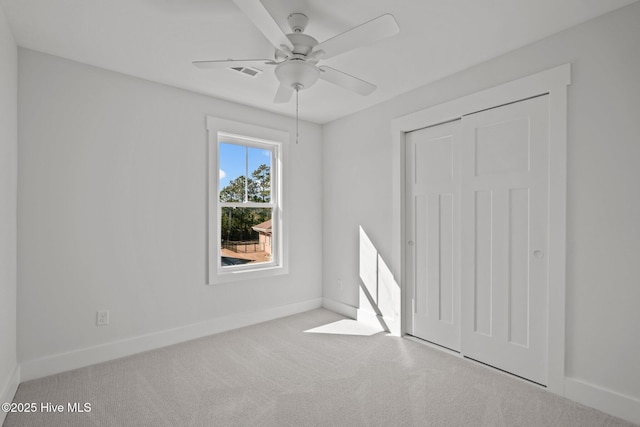 unfurnished bedroom with light carpet, ceiling fan, and a closet