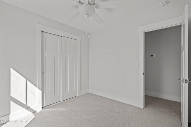 unfurnished bedroom with ceiling fan, light colored carpet, and a closet