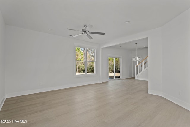 unfurnished living room with ceiling fan with notable chandelier and light hardwood / wood-style floors