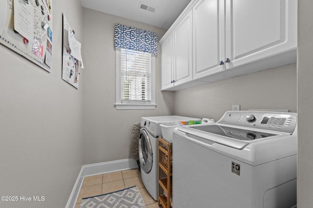 laundry area featuring cabinets, light tile patterned floors, and washing machine and clothes dryer