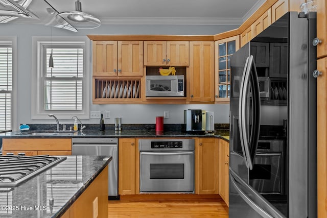 kitchen featuring crown molding, stainless steel appliances, sink, and dark stone counters