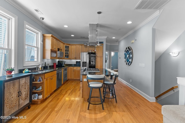 kitchen with sink, decorative light fixtures, ornamental molding, appliances with stainless steel finishes, and a kitchen island