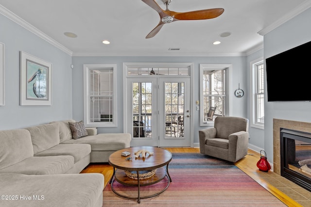 living room featuring a tile fireplace, ornamental molding, and a wealth of natural light