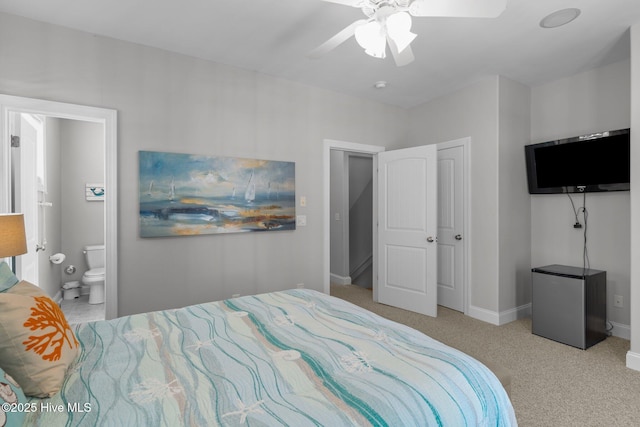 carpeted bedroom featuring connected bathroom, stainless steel refrigerator, and ceiling fan