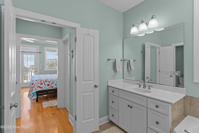 bathroom featuring vanity, hardwood / wood-style floors, toilet, and a tub to relax in