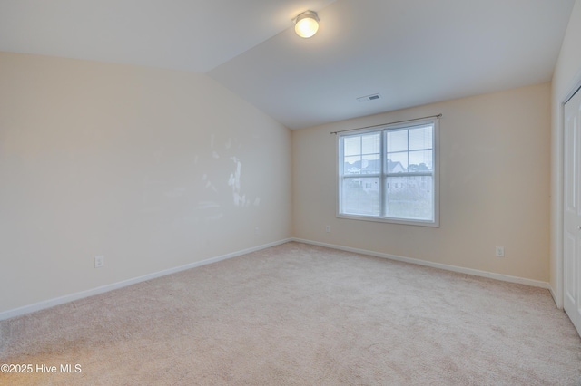 carpeted empty room featuring vaulted ceiling