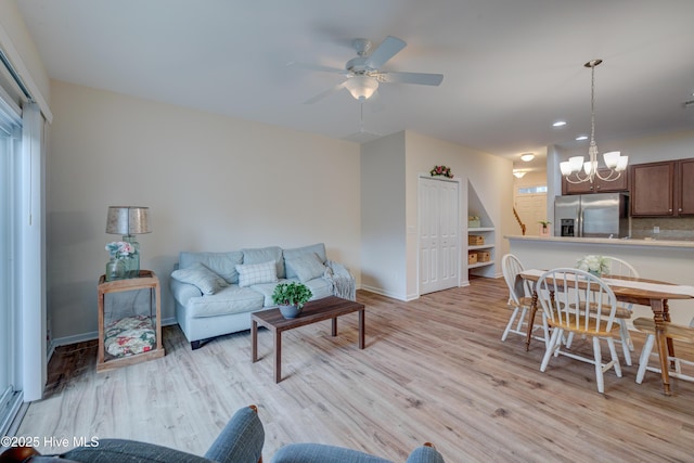 living room with ceiling fan with notable chandelier and light wood-type flooring