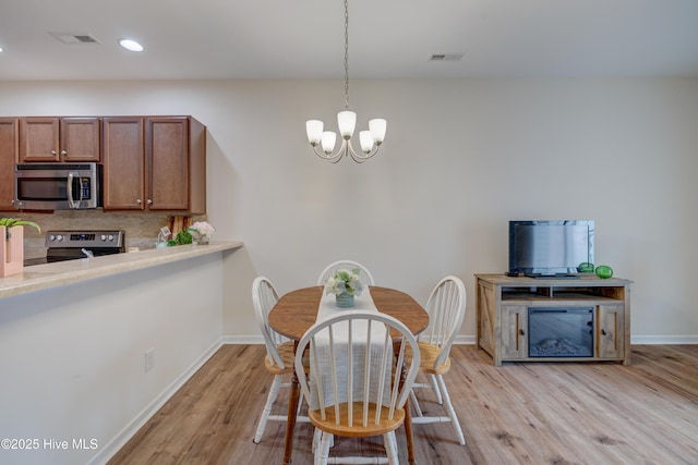 dining area with a chandelier and light wood-type flooring