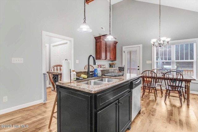 kitchen featuring sink, dishwasher, a kitchen breakfast bar, a center island with sink, and decorative light fixtures