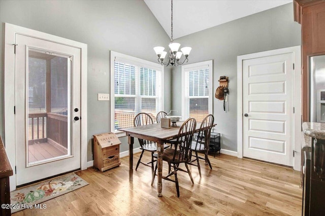 dining area with lofted ceiling, a notable chandelier, and light wood-type flooring