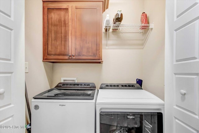 washroom featuring cabinets and washer and clothes dryer