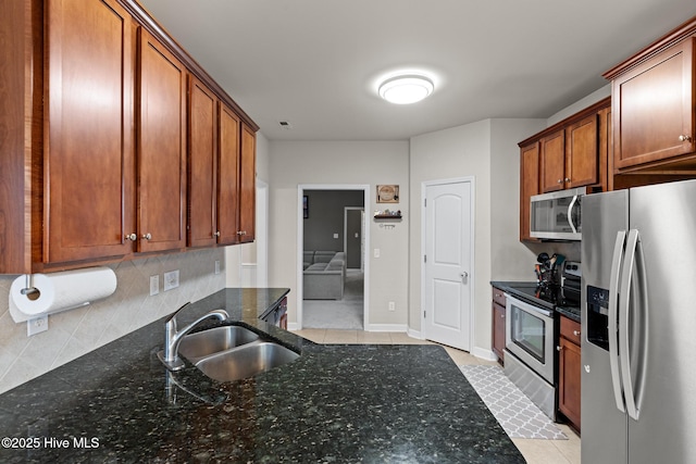 kitchen featuring sink, light tile patterned floors, appliances with stainless steel finishes, tasteful backsplash, and dark stone counters