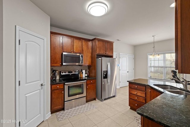 kitchen featuring sink, decorative light fixtures, light tile patterned floors, stainless steel appliances, and backsplash