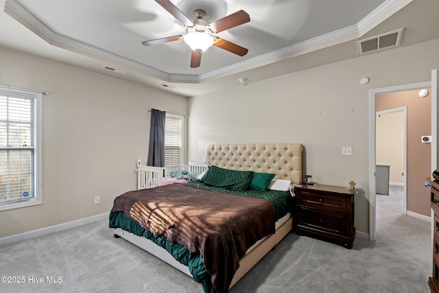 carpeted bedroom featuring ornamental molding, a tray ceiling, and multiple windows