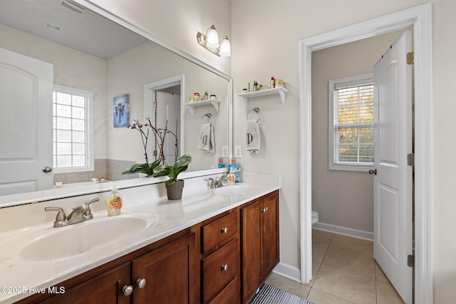 bathroom with a healthy amount of sunlight, toilet, tile patterned flooring, and vanity