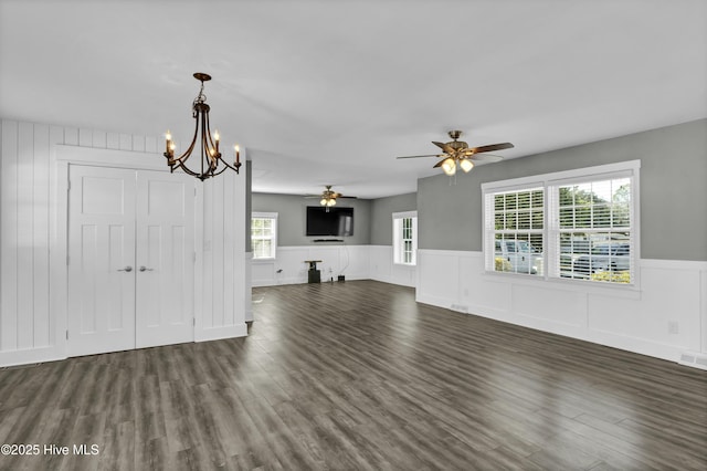 unfurnished living room featuring ceiling fan with notable chandelier and dark hardwood / wood-style floors