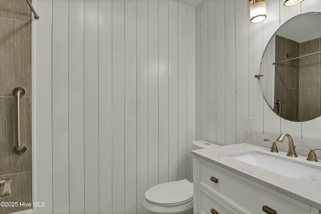 bathroom with vanity, tiled shower, and toilet