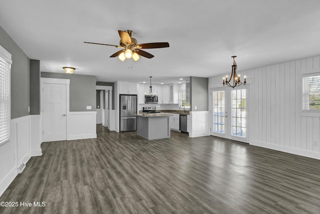 unfurnished living room with sink, ceiling fan with notable chandelier, dark hardwood / wood-style floors, and french doors