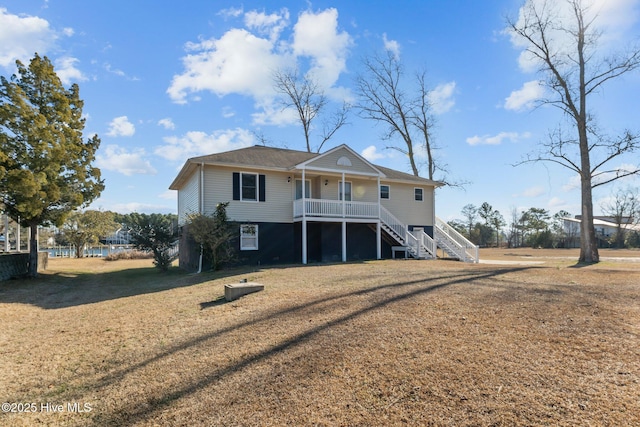 rear view of property featuring a porch and a lawn