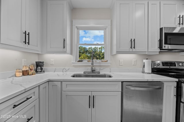 kitchen featuring stainless steel appliances, sink, white cabinets, and light stone counters