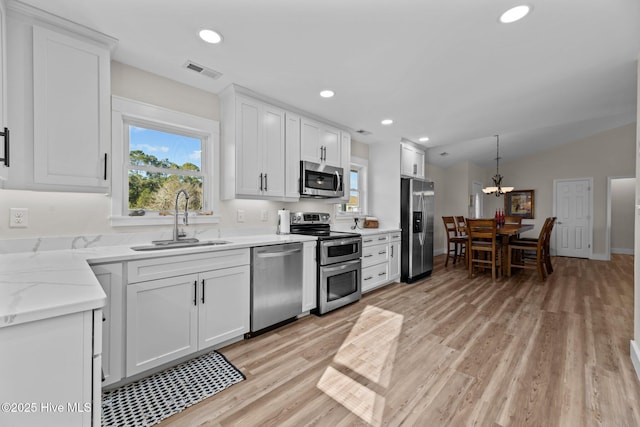 kitchen with stainless steel appliances, decorative light fixtures, sink, and white cabinets