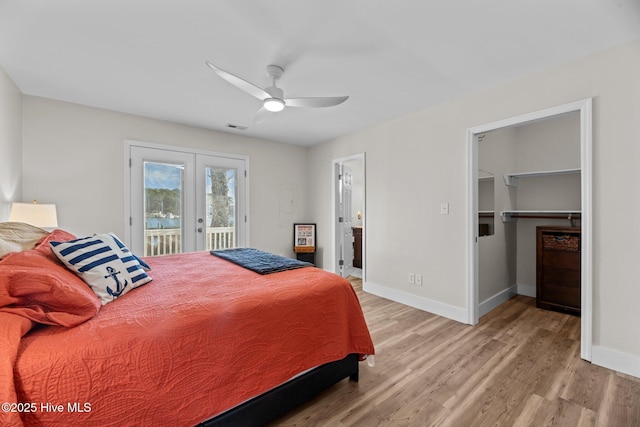 bedroom featuring a spacious closet, access to exterior, ceiling fan, light hardwood / wood-style floors, and french doors