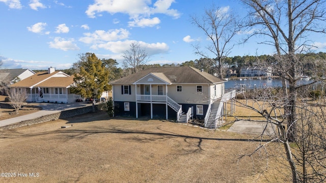 view of front of property featuring covered porch, a front yard, and a water view