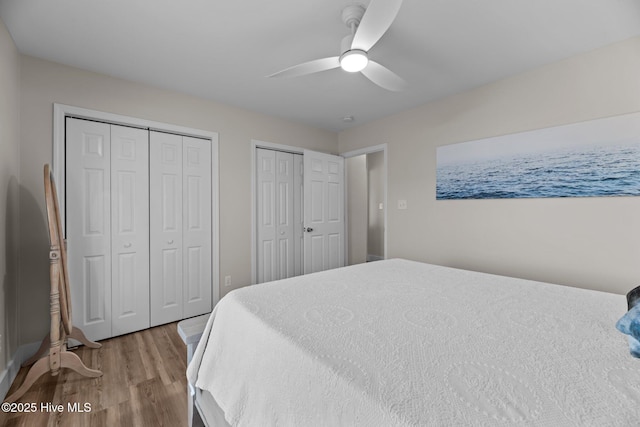 bedroom with two closets, wood-type flooring, and ceiling fan