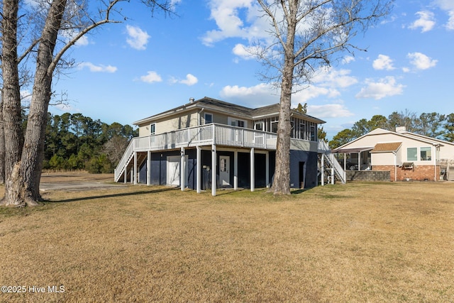 rear view of house with a lawn, a sunroom, and a deck