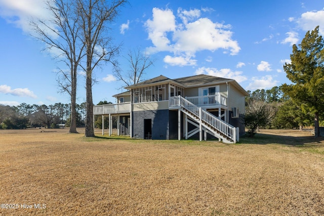 back of house with a sunroom, a deck, and a lawn