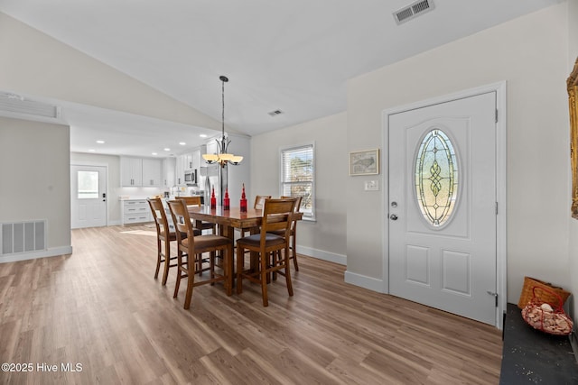 dining area featuring lofted ceiling, a notable chandelier, light hardwood / wood-style flooring, and plenty of natural light